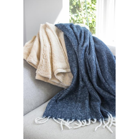 Couvertures en textile doux beige et bleu disposées sur un canapé près d’une fenêtre.