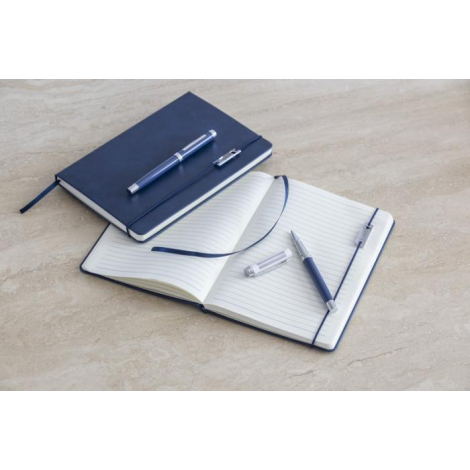 Ensemble carnet bleu marine et stylo roller assorti, carnet ouvert sur pages lignées, marquage visible sur le corps et le boucho