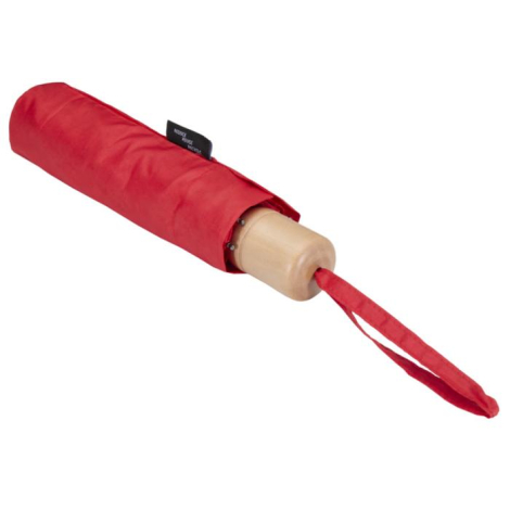 Parapluie rouge replié dans sa housse assortie, posé à plat, poignée bois claire et dragonne en tissu rouge.