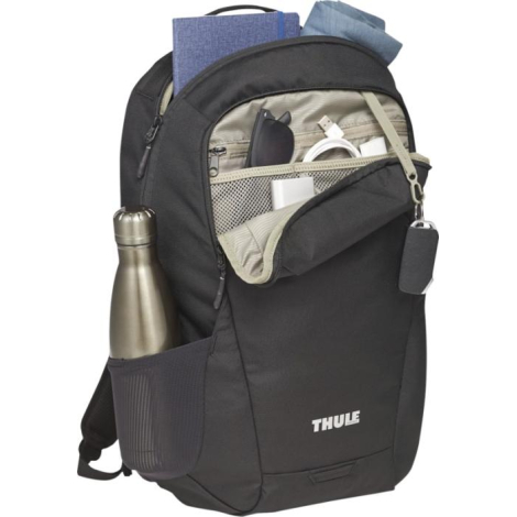 Sac à dos noir ouvert montrant l’intérieur garni d’objets (gourde, carnet, chargeur, vêtements).