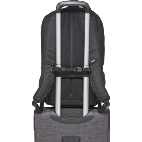 Vue arrière du sac à dos fixé sur la poignée d’une valise grâce à la sangle de maintien.