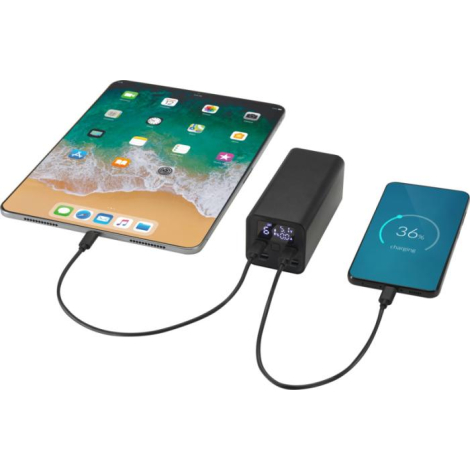Batterie externe noire connectée simultanément à une tablette et un smartphone, affichant le niveau de charge sur son écran LED 