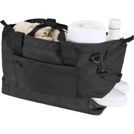 Sac de voyage noir ouvert, contenant des accessoires (serviette, bouteille, chaussures).