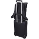 Vue arrière du sac fixé sur la poignée télescopique d’une valise grâce à une sangle horizontale.