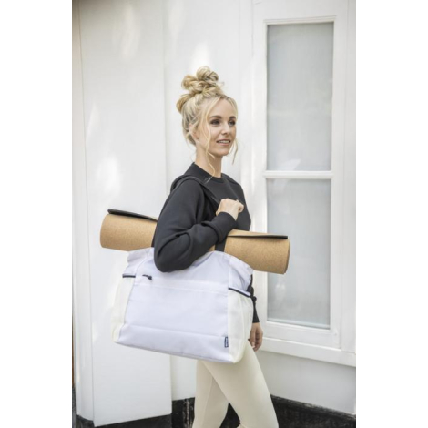 Sac cabas blanc porté à l’épaule par une personne vêtue de clair, avec tapis de yoga fixé sur le dessus ; sans marquage visible. Sac cabas blanc porté à l’épaule par une personne vêtue de clair, avec tapis de yoga fixé sur le dessus ; sans marquage visible.