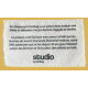 Étiquette blanche cousue sur fond jaune uni, texte noir. Étiquette blanche cousue sur fond jaune uni, texte noir.