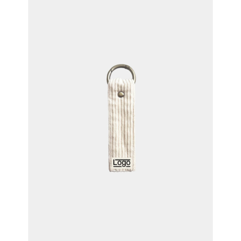 Porte-clés écru texturé avec anneau doré et rivet central, marquage en bas