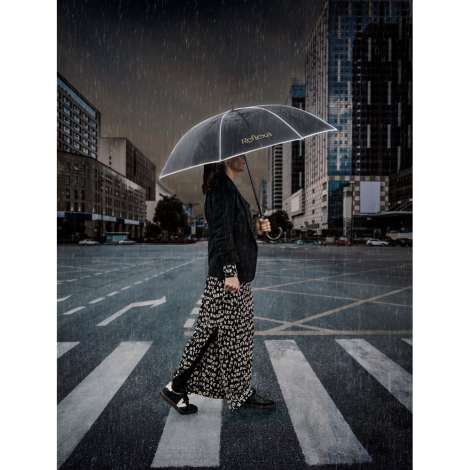 Parapluie noir porté par une personne sous la pluie avec marquage sur un pan de la toile.