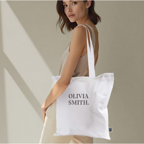 Sac cabas blanc porté à l’épaule, montrant la surface de marquage au dos ; aucune personnalisation visible.