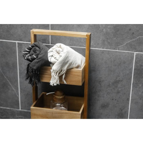 Foutas recyclées noir et blanc roulées et déposées dans une étagère en bois d’une salle de bain, franges et texture tissée visib