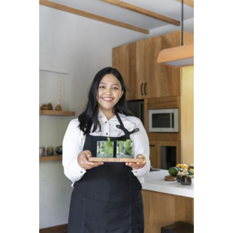 Tablier recyclé noir porté par une personne en cuisine, montrant la longueur, la coupe et la position du lien de cou ; sans marq