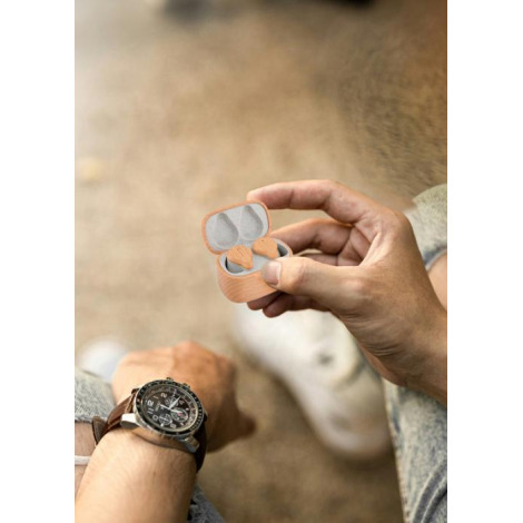Boîtier en finition naturelle tenu dans une main, ouvert avec écouteurs en place ; marquage apparent sur la face avant, aucune a