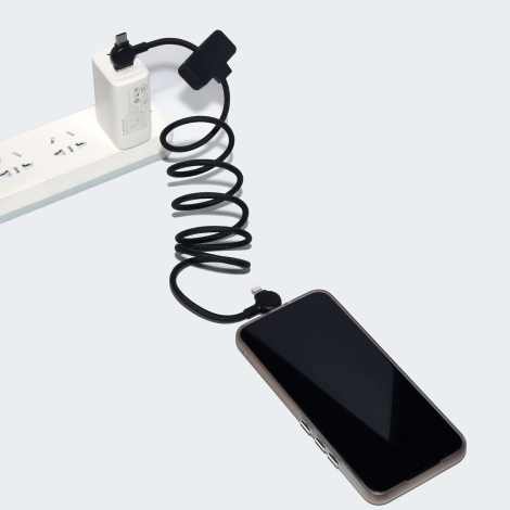 Câble noir en spirale relié à un chargeur et à un smartphone