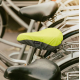 Housse de selle en R-PET installée sur une selle de vélo en extérieur, zone réfléchissante identifiable, sans marquage visible. Housse de selle en R-PET installée sur une selle de vélo en extérieur, zone réfléchissante identifiable, sans marquage visible.