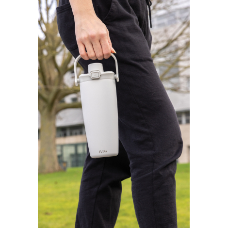 Mug isotherme blanc tenu à la main en extérieur, poignée supérieure utilisée pour le transport, bandoulière non visible, sans ma