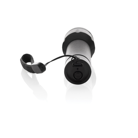 Lampe torche couchée sur fond blanc vue arrière, bouton de commande, port USB-C et fixation de la dragonne visibles, aucune pers