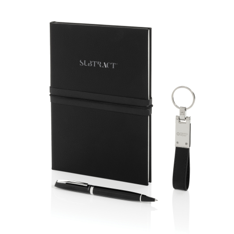 Carnet noir fermé sur fond blanc avec élastique horizontal, accompagné d’un stylo noir et d’un porte-clés avec lanière synthétiq