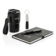 Ensemble bureau sur fond blanc avec mug isotherme noir, carnet noir fermé avec élastique, stylo posé et porte-clés avec partie m