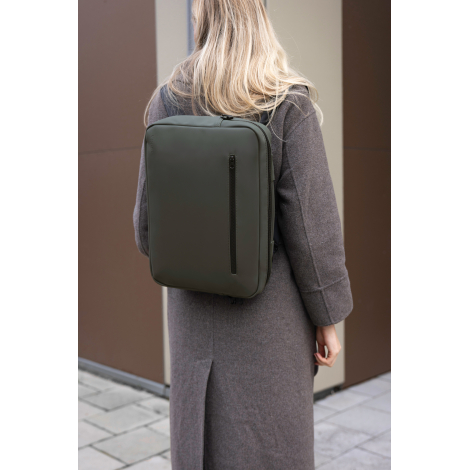 Sac ordinateur porté sur le dos par une femme en environnement urbain, modèle vert foncé avec fermeture zippée verticale visible
