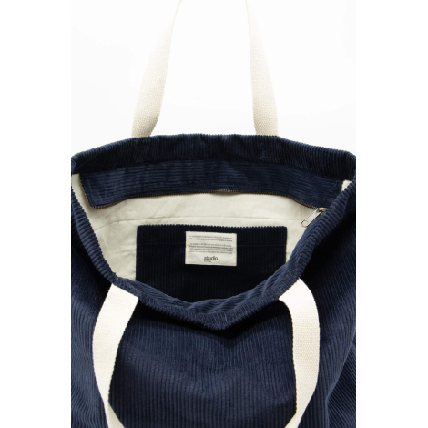 Vue intérieure du sac bleu foncé montrant la doublure claire et l’étiquette cousue.