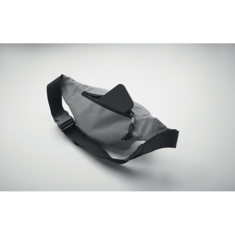 Sac banane présenté en perspective sur fond clair, avec smartphone partiellement inséré dans un compartiment zippé, dessus du sa