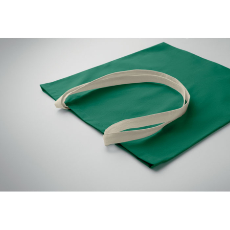 Sac shopping en coton posé à plat, vue de dessus et de biais, longues poignées et surface textile visibles, sans marquage visibl