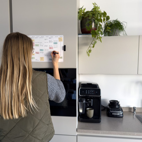 Calendrier hebdomadaire adhésif utilisé dans un environnement partagé, avec inscriptions manuscrites visibles.