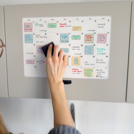 Planificateur mensuel adhésif en cours d’effaçage, avec inscriptions encore visibles.