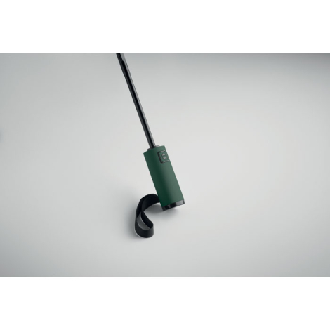 Gros plan sur la poignée d’un parapluie ouvert vert avec dragonne noire, présenté sur fond clair, sans personnalisation visible.