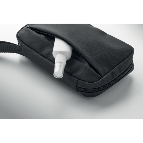 Vue rapprochée d’un flacon partiellement inséré dans la poche avant zippée de la trousse noire, sans marquage visible sur cette 