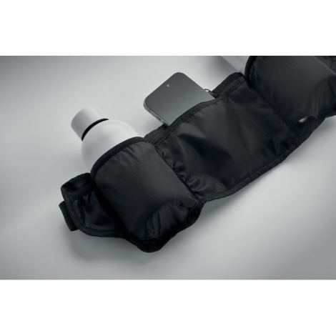 Ceinture en situation avec bouteille insérée dans une poche latérale et smartphone partiellement visible dans la poche centrale,