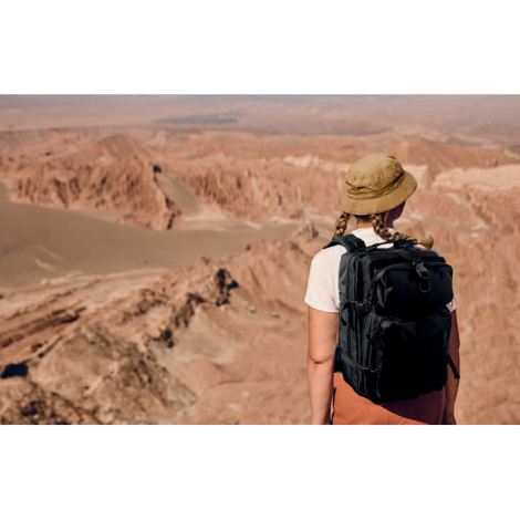 Sac à dos porté par une personne en extérieur, vu de dos dans un paysage désertique, sans marquage apparent.