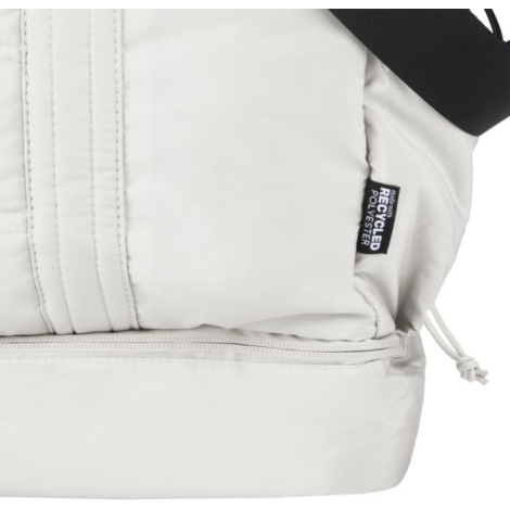 Vue rapprochée du côté d’un sac de sport beige avec étiquette latérale, sans personnalisation visible.