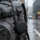 Dispositif accroché à un sac à dos en extérieur sous la pluie, en situation d’utilisation, sans personnalisation apparente.