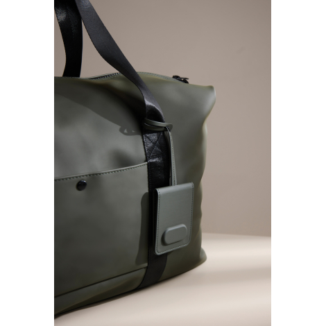 Étiquette attachée à un sac de voyage en situation d’usage, sans marquage visible.