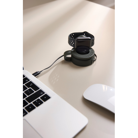Chargeur utilisé sur un bureau avec une montre connectée en cours de recharge, en situation d’usage, sans marquage visible.