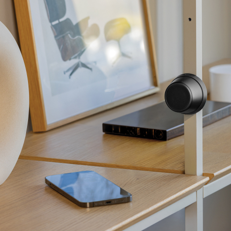 Haut-parleur fixé sur une surface métallique en intérieur avec smartphone à proximité, en situation d’usage, sans personnalisati