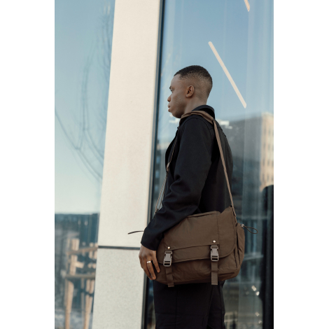 Sac messager porté en bandoulière par un homme en extérieur, illustrant l’usage en déplacement, sans personnalisation visible.