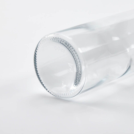 Détail du fond d’une bouteille en verre transparente couchée, focus sur la base, sans marquage apparent