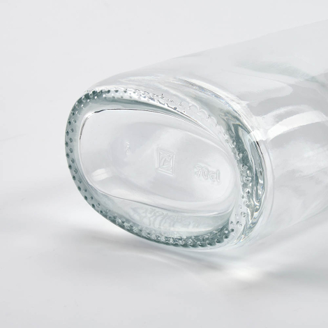 Gros plan sur le fond d’une bouteille en verre couchée mettant en avant la base, sans marquage apparent