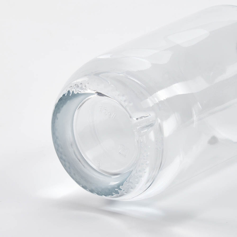 Gros plan sur le fond d’une bouteille en verre couchée mettant en avant la base, sans marquage apparent