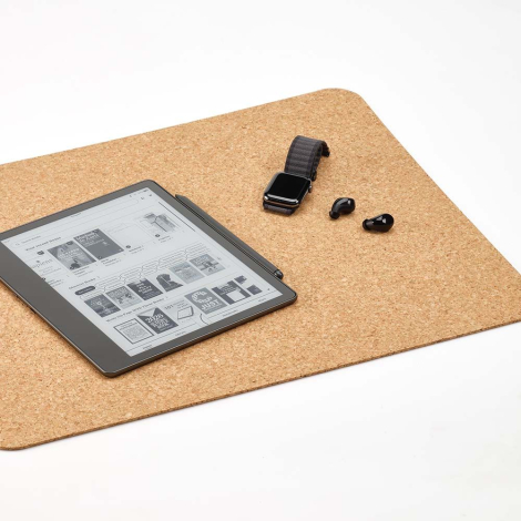 Sous-main en liège utilisé sur un bureau avec liseuse, montre et écouteurs posés dessus, sans marquage apparent