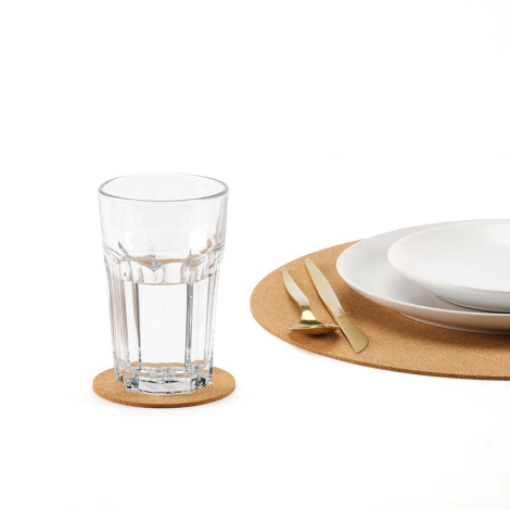 Sous-verre en liège utilisé sous un verre sur une table dressée avec assiette et couverts, sans marquage apparent