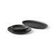 Ensemble d’assiettes plates en céramique noires empilées sur une surface, sans marquage visible