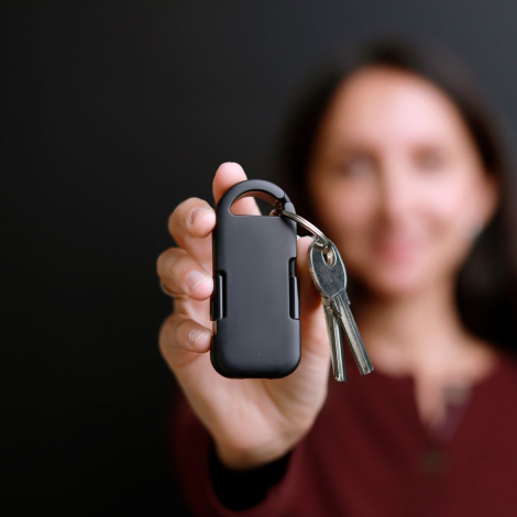 Powerbank noire tenue en main par une femme avec trousseau de clés attaché, sans personnalisation apparente