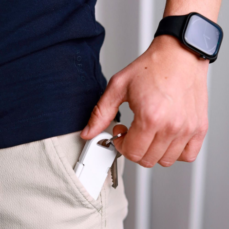 Powerbank blanche partiellement insérée dans une poche tenue en main avec clés attachées, sans marquage visible