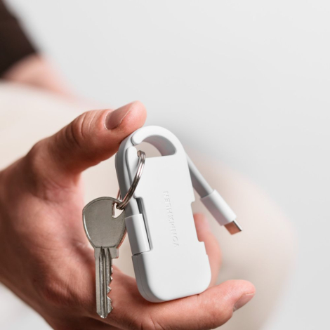 Powerbank blanche tenue en main avec câble intégré visible et clés attachées, sans personnalisation apparente