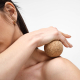 Balle en liège utilisée en massage sur l’épaule d’une femme, sans marquage apparent