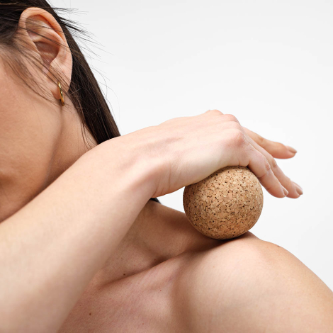 Balle en liège utilisée en massage sur l’épaule d’une femme, sans personnalisation apparente