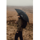 Personne avec sac à dos tenant un parapluie ouvert en extérieur, sans marquage visible